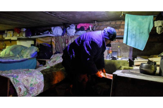 Una mujer pone leña en la estufa para calentar el sótano donde vive con sus vecinos en Siversk. OLEG PETRASYUK