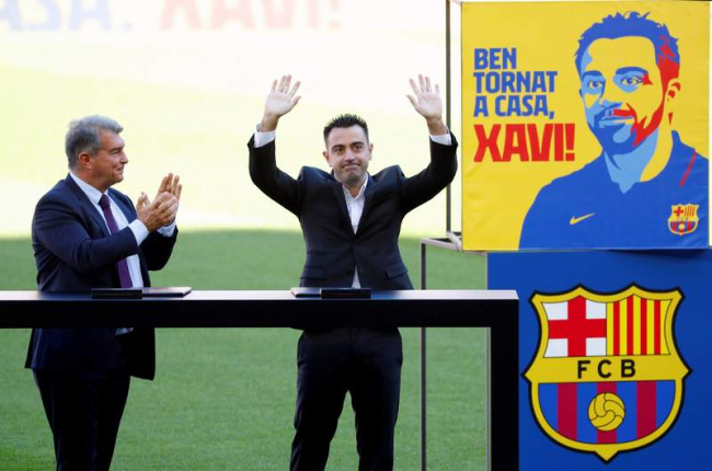 El presidente del Barcelona, Joan Laporta, aplaude a Xavi Hernández, durante la presentación de ayer en el Camp Nou. ALEJANDRO GARCÍA