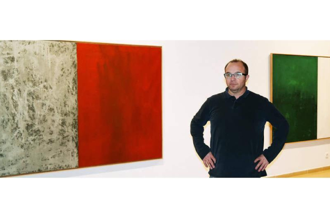 El artista coyantino posa ante dos obras de la exposición ‘Intuición’ que exhibe en el Instituto Leonés de Cultura.