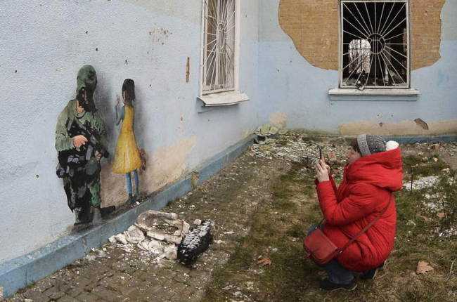 Una mujer fotografía una pintura en un muro de Jarkov. ANDRII NESTERENKO