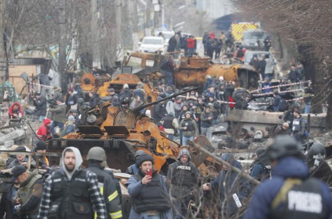 Periodistas caminan por una calle de Bucha entre material bélico ruso destruido. SERGEY DOLZHENKO