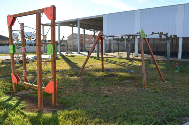 Imagen del parque infantil de Toral de los Guzmanes, con el pabellón polideportivo al fondo. MEDINA