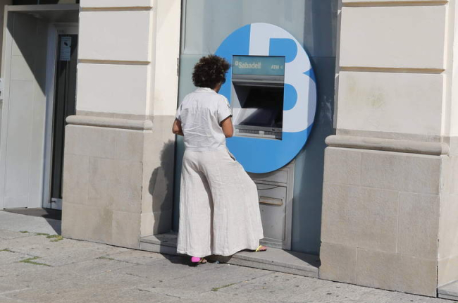 Una clienta saca dinero de un cajero automático de una entidad. RAMIRO