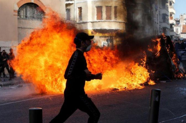 Unos jóvenes queman contenedores de basura en Marsella durante una manifestación contra los planes fiscales del Gobierno francés.