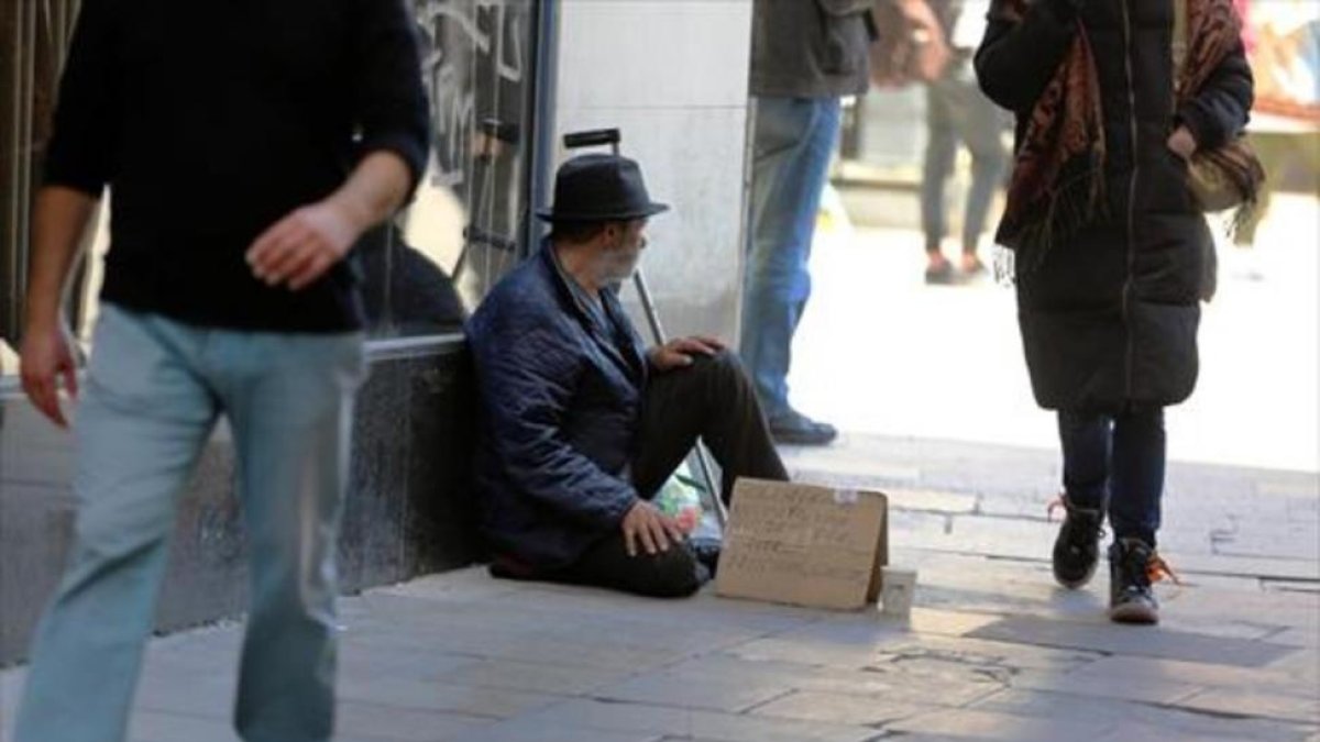 Un indigente pide ayuda a los traseúntes en una imagen de archivo.