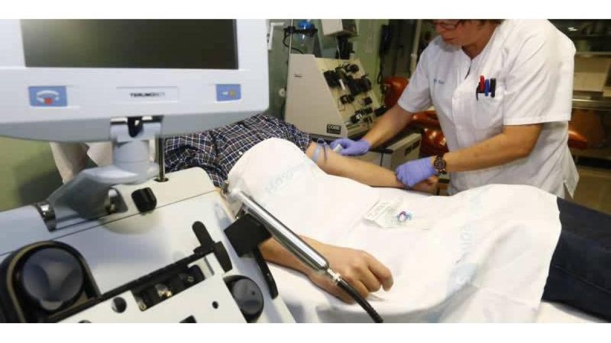 Una enfermera pone el tratamiento a un paciente en el Hospital de León.