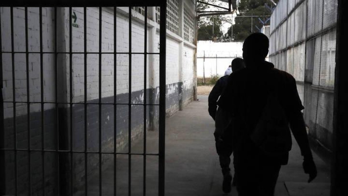 Reclusos caminan por un pasillo.