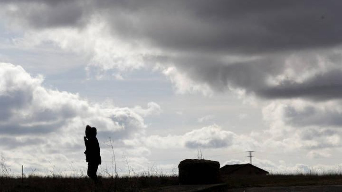 Una persona camina bajo un cielo cubierto de nubes en León.