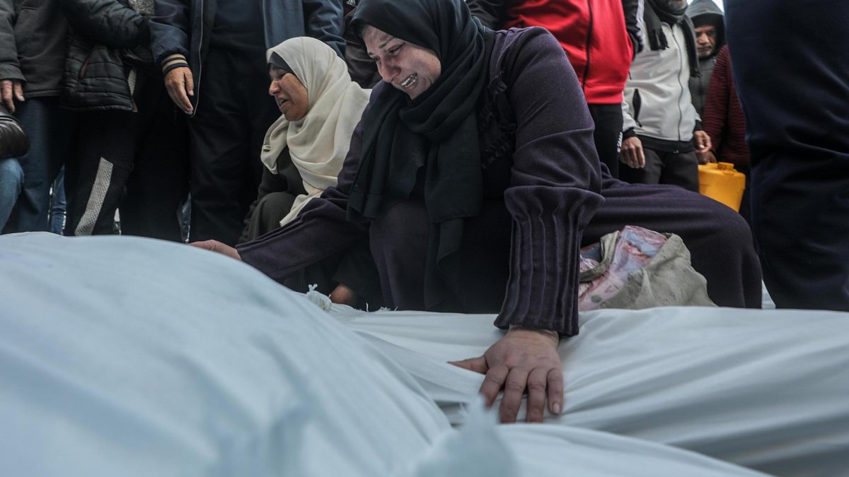 Una mujer palestina llora sobre los cuerpos cubiertos de los miembros de una familia palestina asesinados en un ataque aéreo israelí, en el Hospital de los Mártires de Al Aqsa en la ciudad de Deir Al Balah, en el centro de la Franja de Gaza, 15 de enero de 2025. 
                       EFE/EPA/MOHAMMED SABER