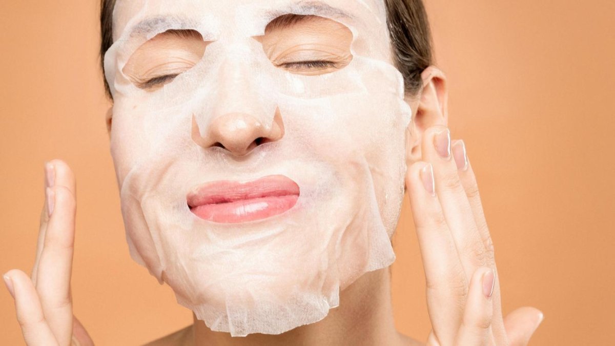 Una mujer se coloca una mascarilla en el rostro.