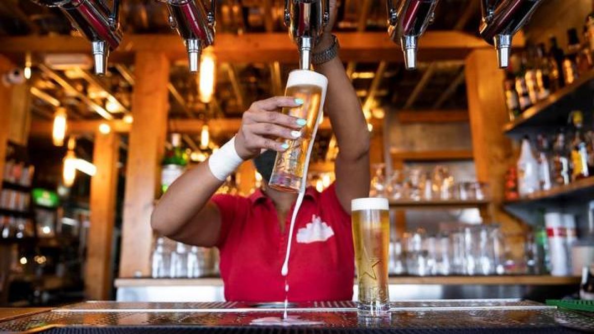 Una camarera sirve unas cervezas en un bar.