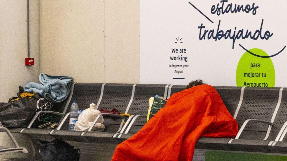 Una persona sin techo duerme en un aeropuerto.