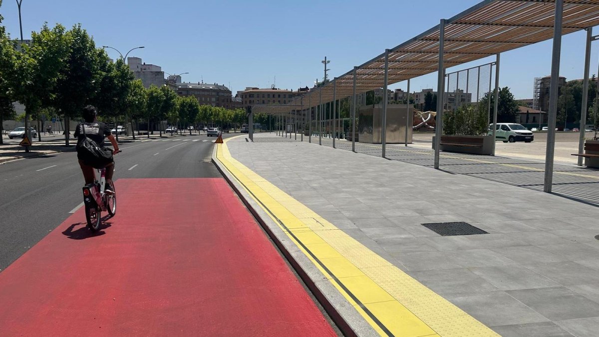 Nueva señalización horizontal de tráfico roja recientemente incorporada en Eras de Renueva, frente a la pérgola bioclimátiaca en construcción.