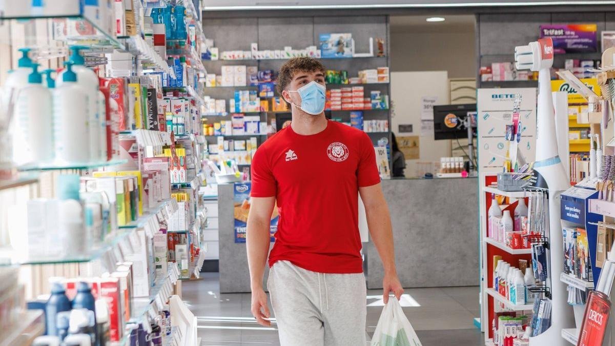 Un joven compra en una farmacia de León protegido por la mascarilla, ayer.