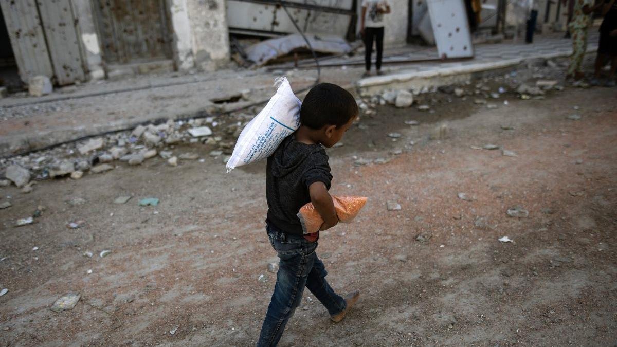 Un niño recoge harina y pan en Gaza.