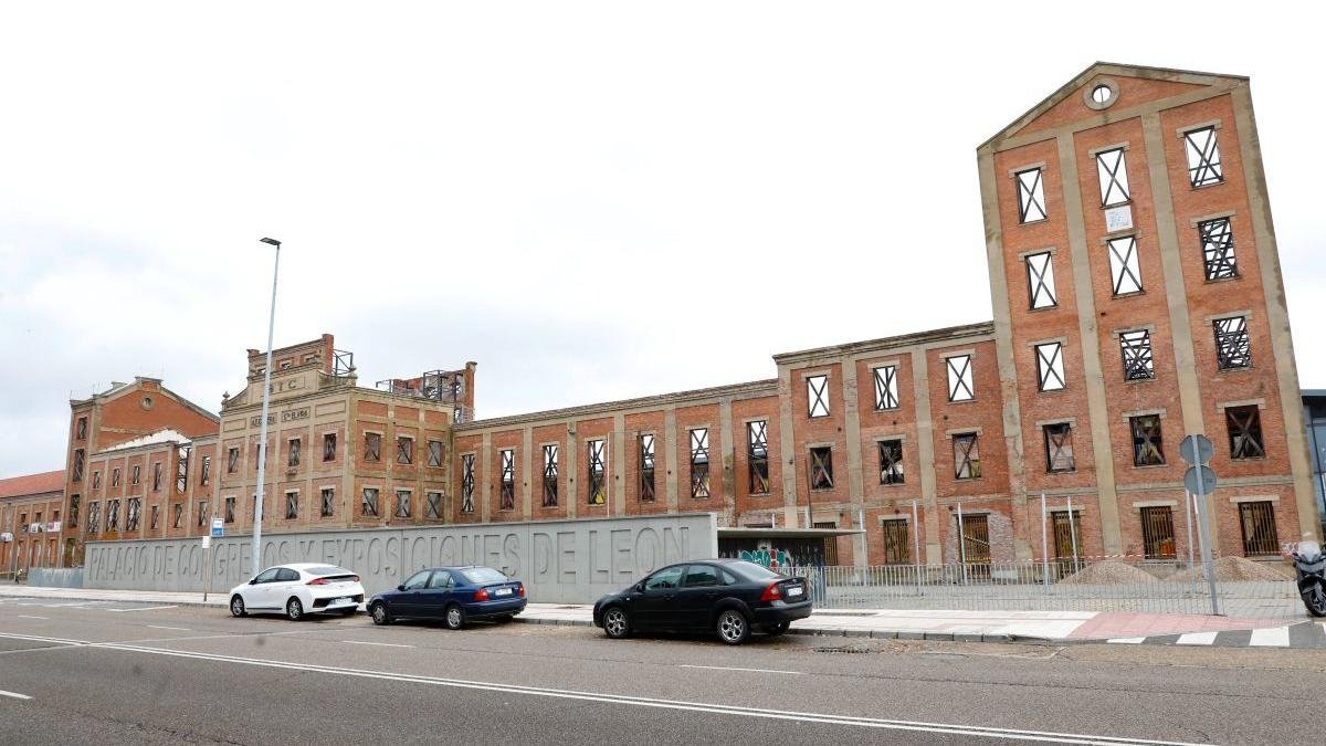 La fachada de la antigua Azcarera Santa Elvira luce ya sin andamios después de 16 años amparados los muros. A la derecha, imagen de las máquinas que trabajan este domingo para adelantar la entrega del trampantojo de lo que iba a ser el Palacio de Congresos de León.