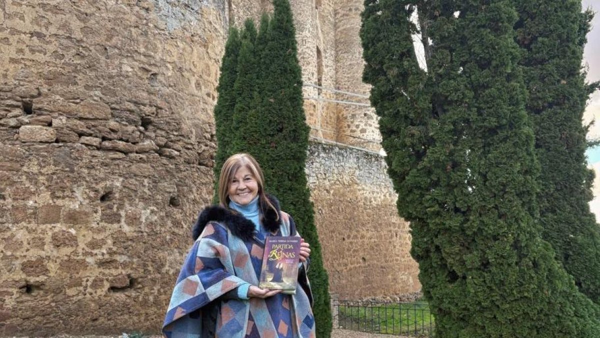 La escritora María Teresa Álvarez con su libro ante el castillo de Valencia de don Juan.