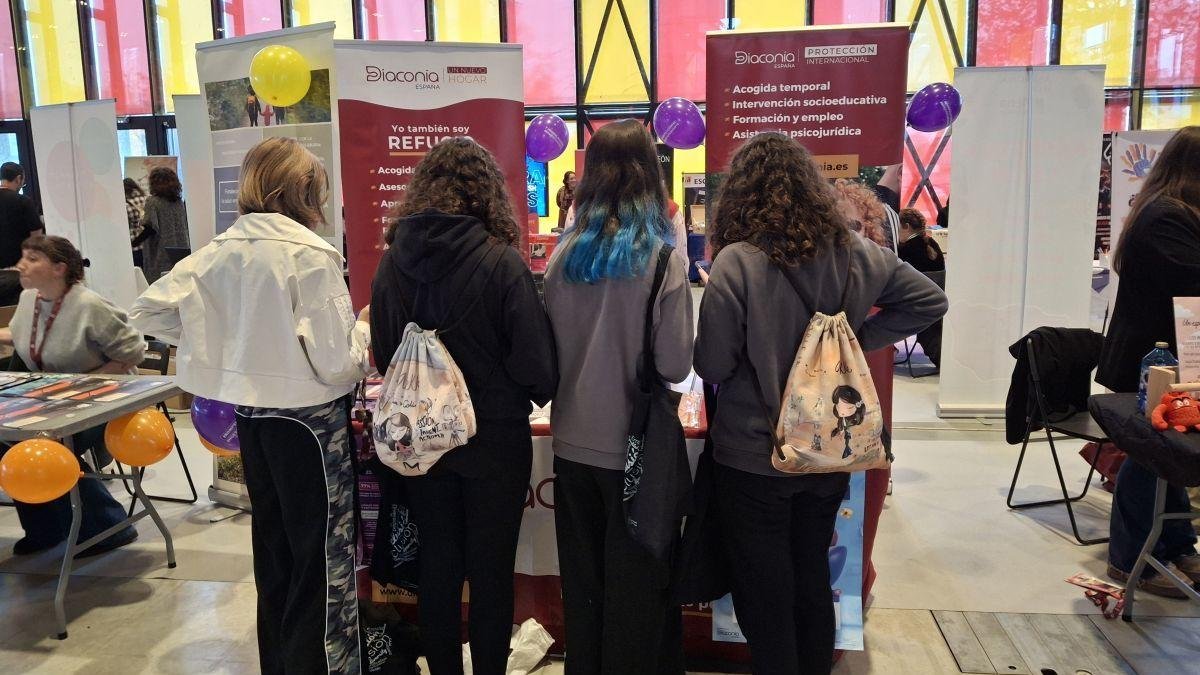 Cuatro chicas se acercan a Diaconía en la Expojoven para participar en el juego interactivos con información sobre la trata.