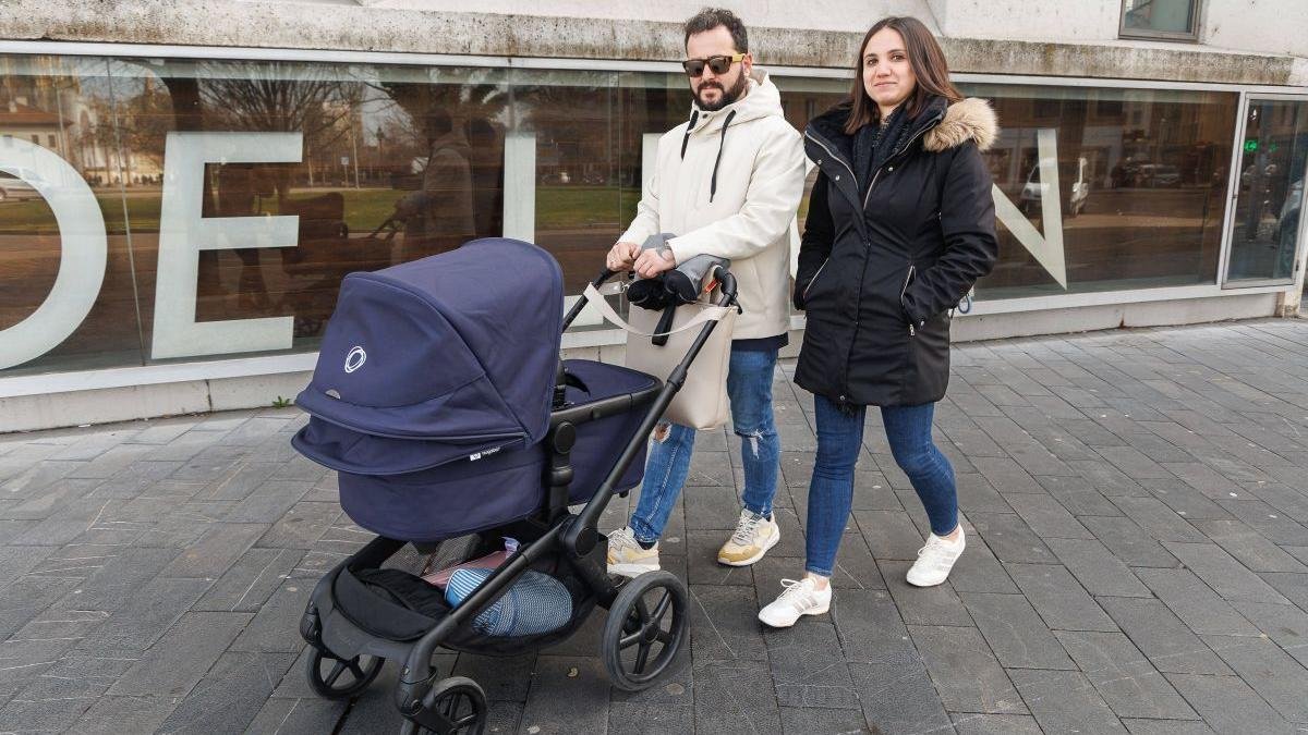 Una pareja camina frente al Auditorio Ciudad de León con su bebé en el carrito.