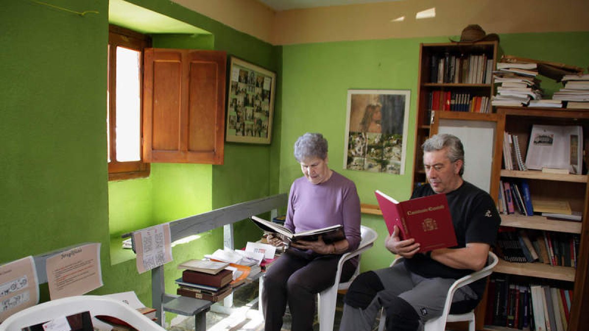 Dos vecinos consultan sendos ejemplares en la biblioteca de Valdorria.