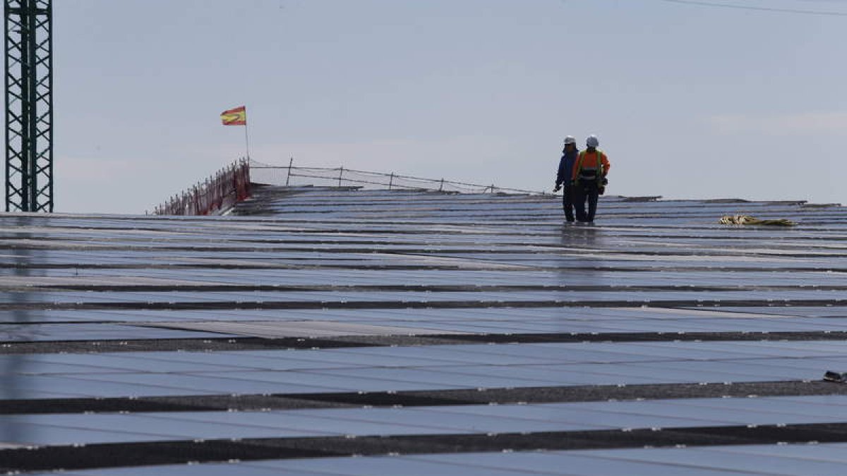 Dos operarios trabajan en un tejado cubierto de placas solares. RAMIRO
