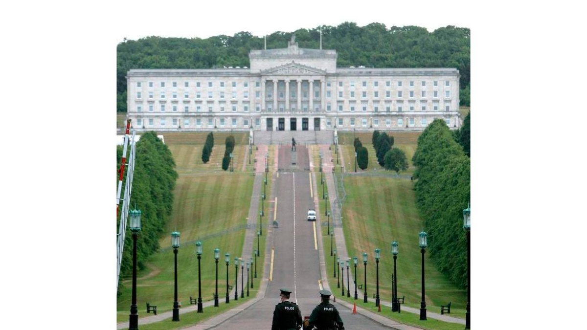 Vista del Stormont, sede del Gobierno (arriba); imagen de una sala del interior del museo Titanic Belfast (medio); varios hombres pasean delante de murales pintados en las calles de la capital.