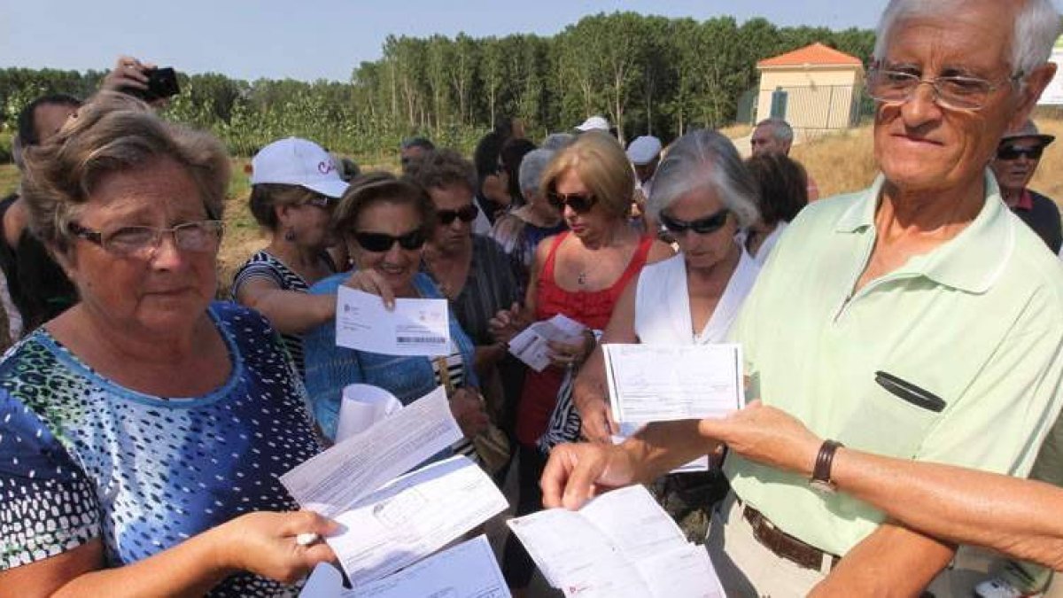 Vecinas y vecinos de Celada protestan con sus recibos por el pago de la depuración de aguas residuales frente a la estación de San Justo de la Vega, aguas arriba de su pueblo.