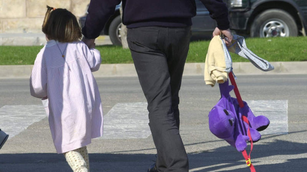 Un padre lleva a su hija de la mano tras recogerla a la salida del colegio.