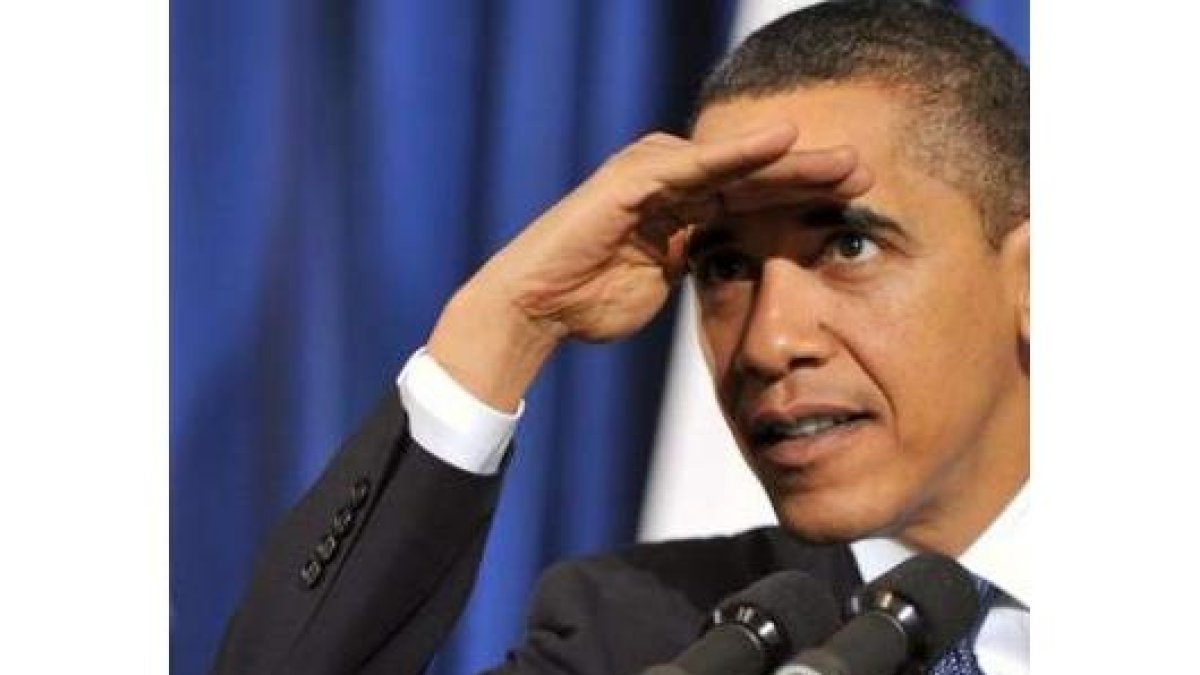 Obama se cubre los ojos para evitar el reflejo de los focos mientras escucha una pregunta.