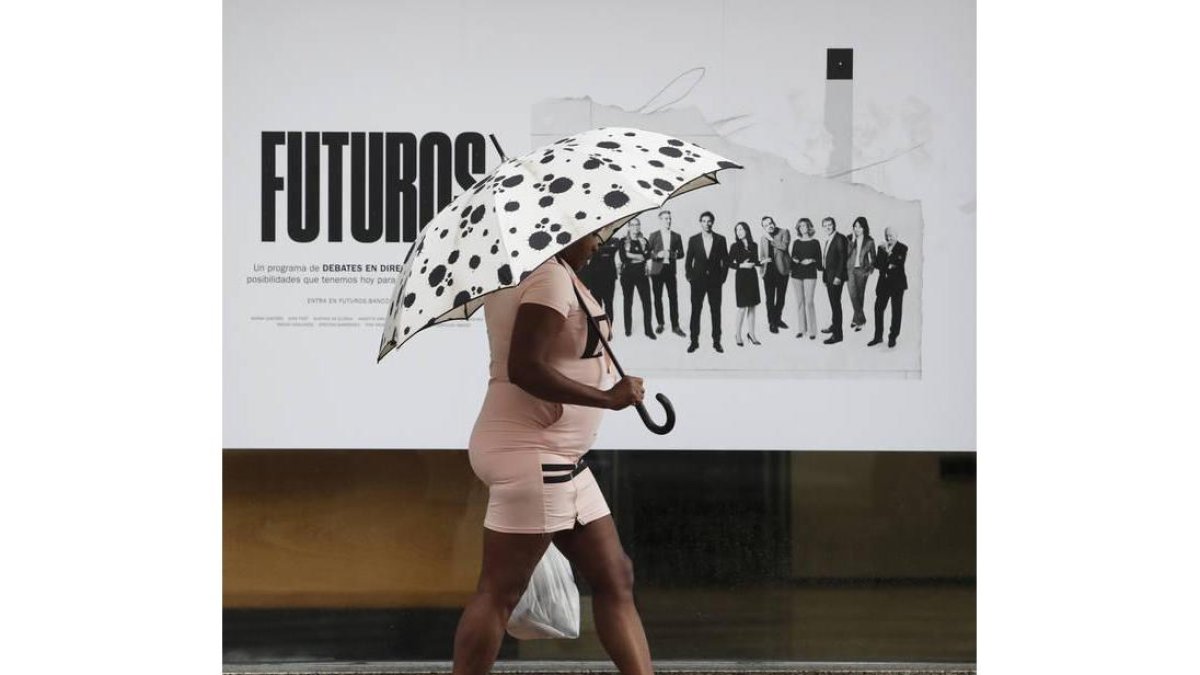 Una mujer se protege de la lluvia en uno de los temporales de este verano en León.