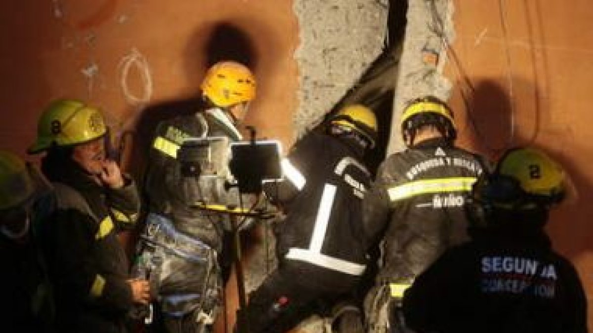 Bomberos chilenos buscan supervivientes entre los escombros.