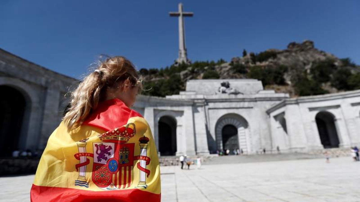 Una mujer envuelta en una bandera española en la explanada del Valle de los Caídos. MARISCAL