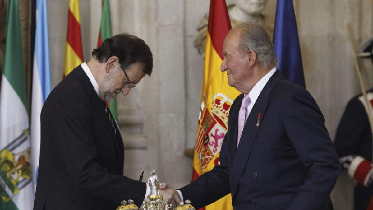 El presidente del Gobierno estrecha la mano del rey tras la firma del documento.
