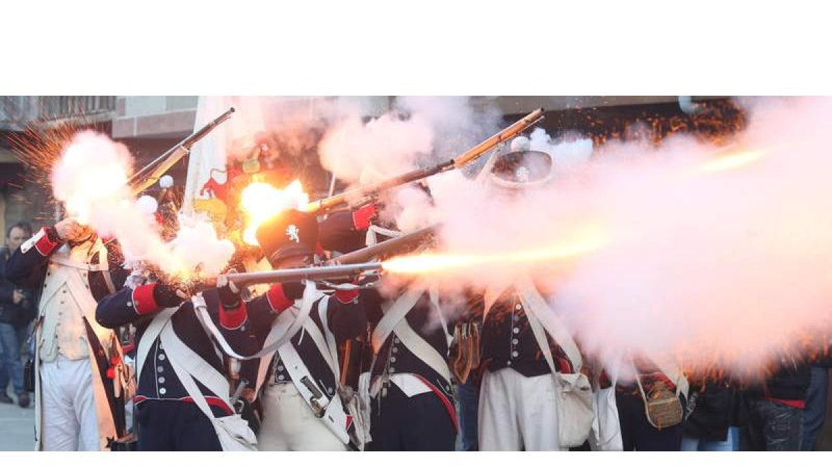 Tropas francesas disparan sus mosquetes contra las inglesas y españolas en la recreación de la refriega por las calles de Cacabelos.