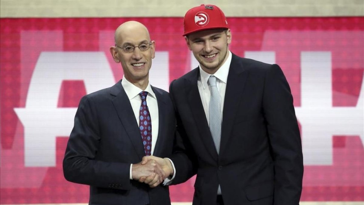 Luka Doncic saluda en el estrado a Adam Silver, comisionado de la NBA, tras su elección.