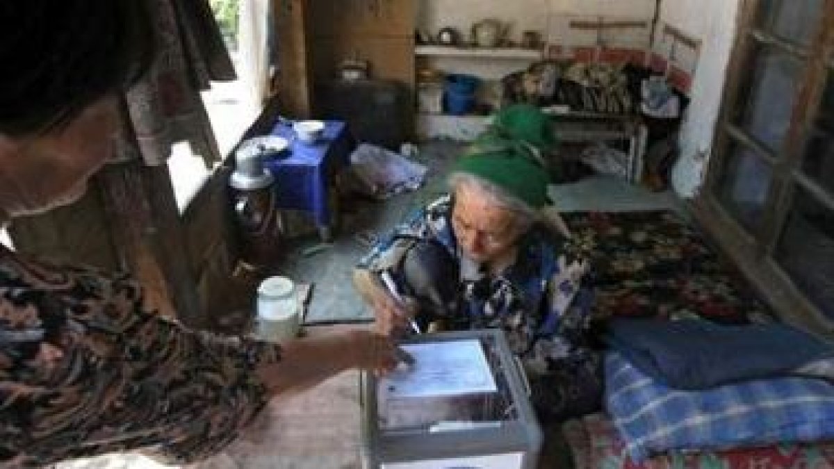 Una anciana deposita su voto en una urna móvil en el distrito uzbeko de Unadir.