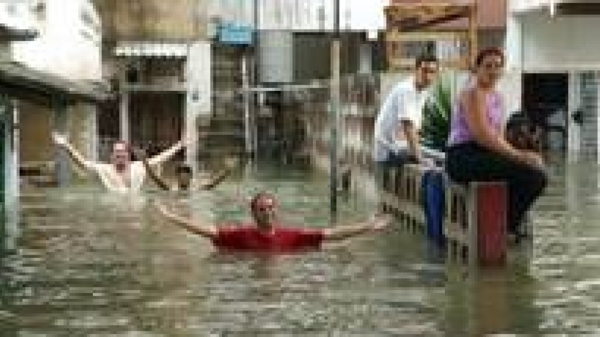 Un grupo de cubanos bromea con los bomberos delante de sus casas