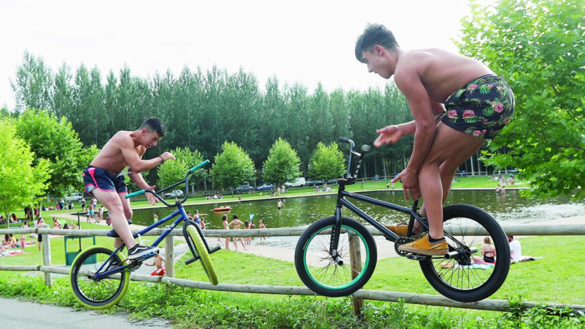 Dos jóvenes vuelan con sus bicicletas junto a la playa fluvial de Villoria de Órbigo. DL
