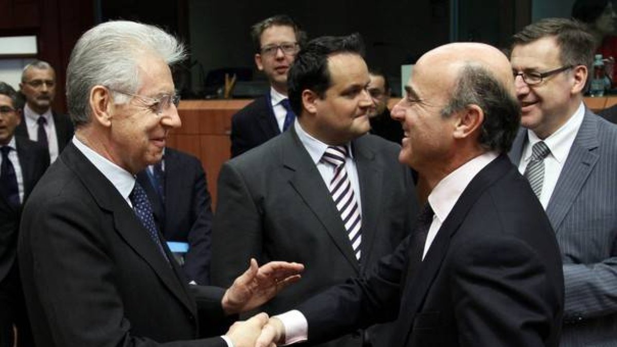 Mario Monti y Luis de Guindos se saludan este lunes en Bruselas.