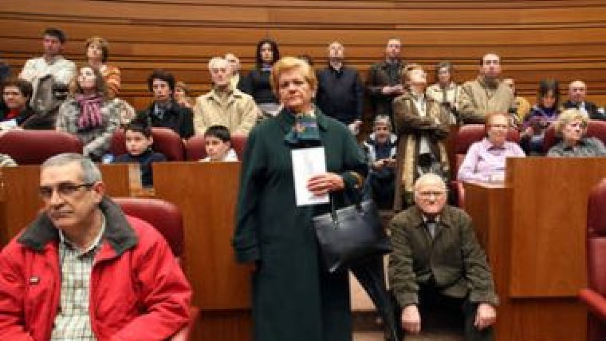 Pequeños sentados en los escaños de las Cortes siguen la visita guiada por el presidente del Parlame