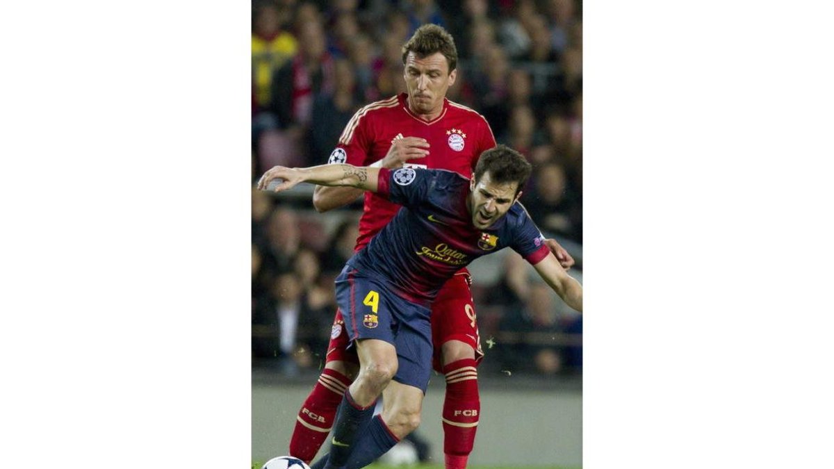 Cesc Fábregas pugna con el delantero croata del Bayern Munich, Mario Mandzukic.