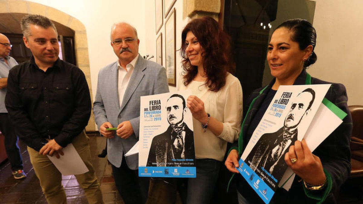 Dos libreras con el cartel de la feria, junto a Santiago Macías y Emilio Cubelos
