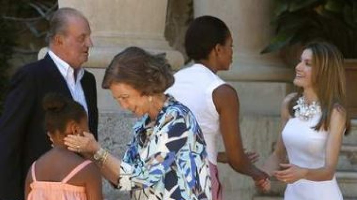 La Reina conversa con la pequeña Sasha mientras el Rey observa el saludo de Michelle Obama y Letizia