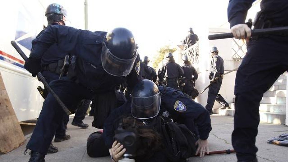 Agentes de la policía de Oakland arrestan a uno de los participantes en la protesta de indignados, el sábado, en el centro de la ciudad.