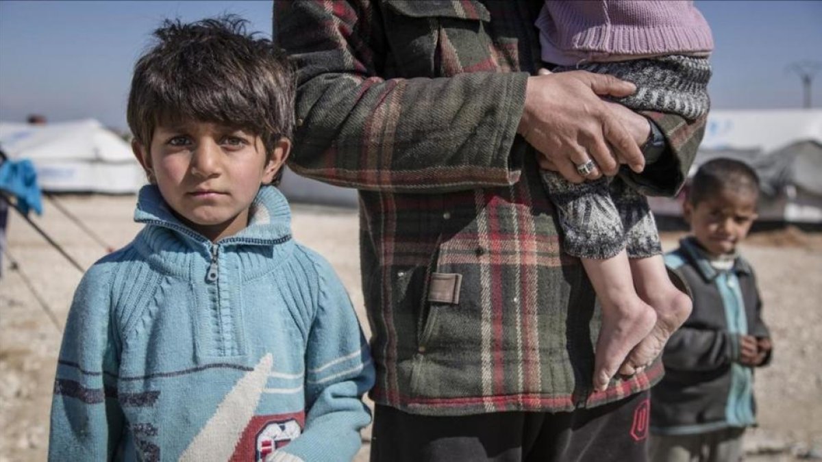 Ibrahim, de 7 años, junto a su padre, profesor de Deir Ezzor, y su hermana Nour, de 2 años (en sus brazos), en el campo de refugiados de Hasakah (Siria).