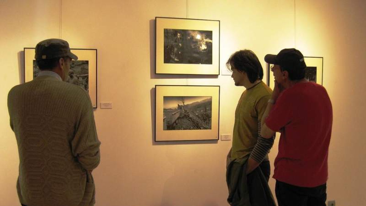 Un grupo de ex mineros busca caras conocidas en las fotografías expuestas.