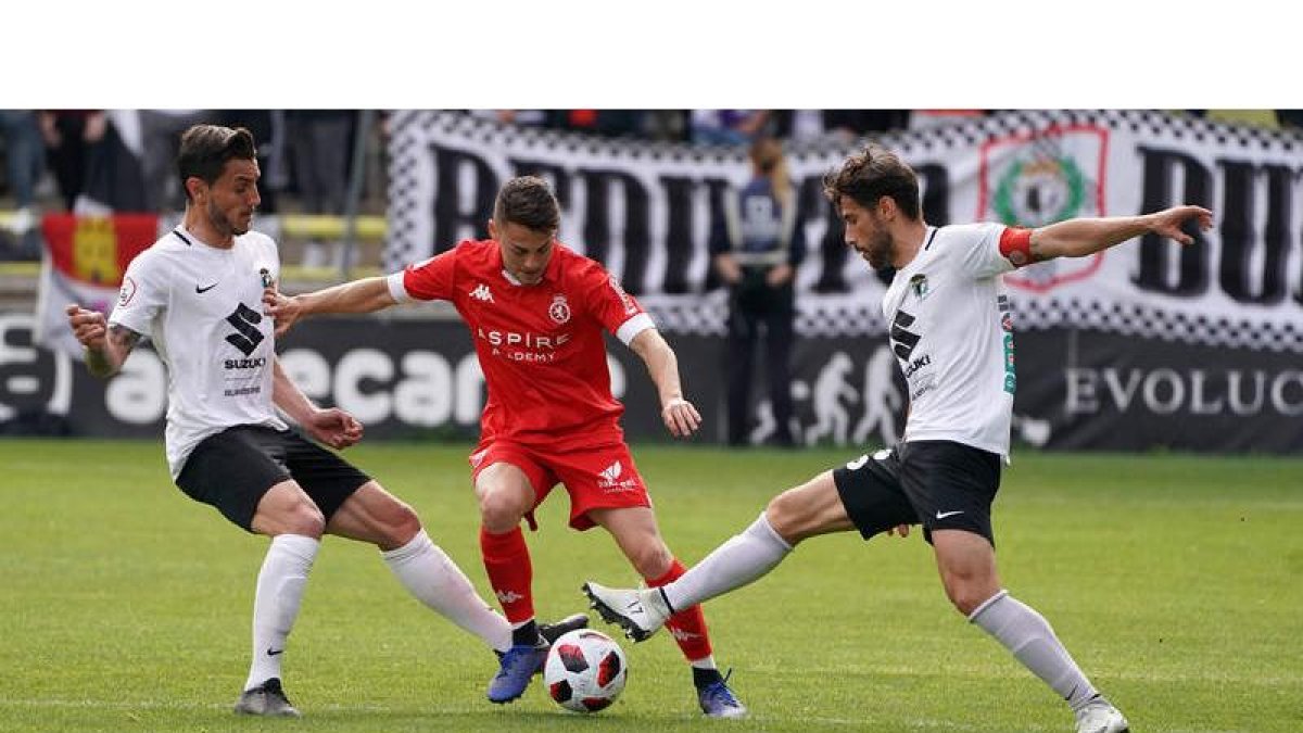 El culturalista Liberto Beltrán, en el centro, trata de irse de dos rivales del Burgos CF en un lance del partido en El Plantío. CÉSAR MANSO