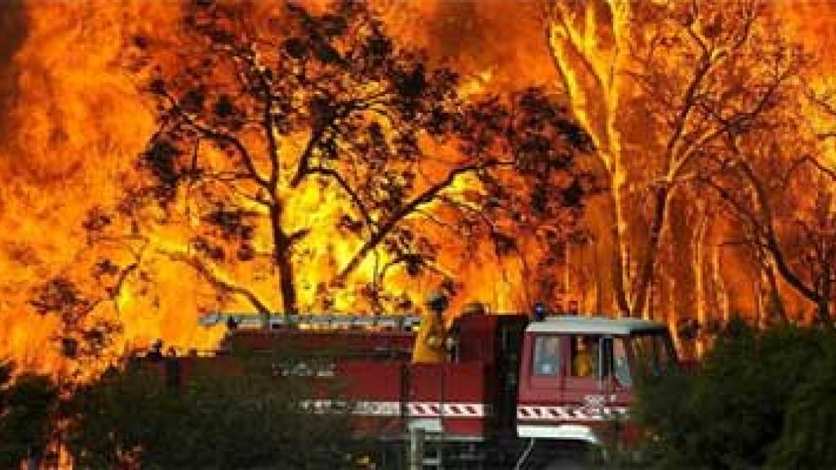 Un carro de bomberos pasa frente a las llamas mientras lucha contra un incendio forestal.