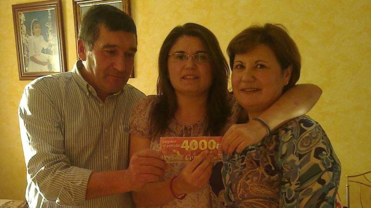 Begoña Seco, con su padre Paulino y su madre Sinda, muestra el vale que encontró en su rosco.