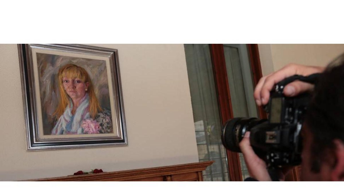 Lienzo de Isabel Carrasco en la galería de retratos de la Diputación Provincial con dos rosas rojas en homenaje. El cuadro fue pintado por Modesto Llamas Gil